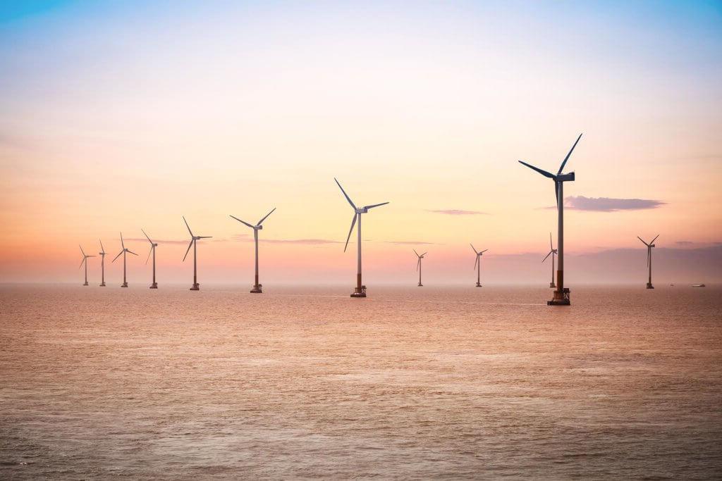 日出时的一系列海上风力涡轮机.
